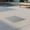Stainless steel square wedgewire floor waste set into paving beside a pool