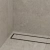 Neston Black Linear Tile Insert Drain In Shower Matte black linear tile insert drain installed along a stone-tiled shower wall