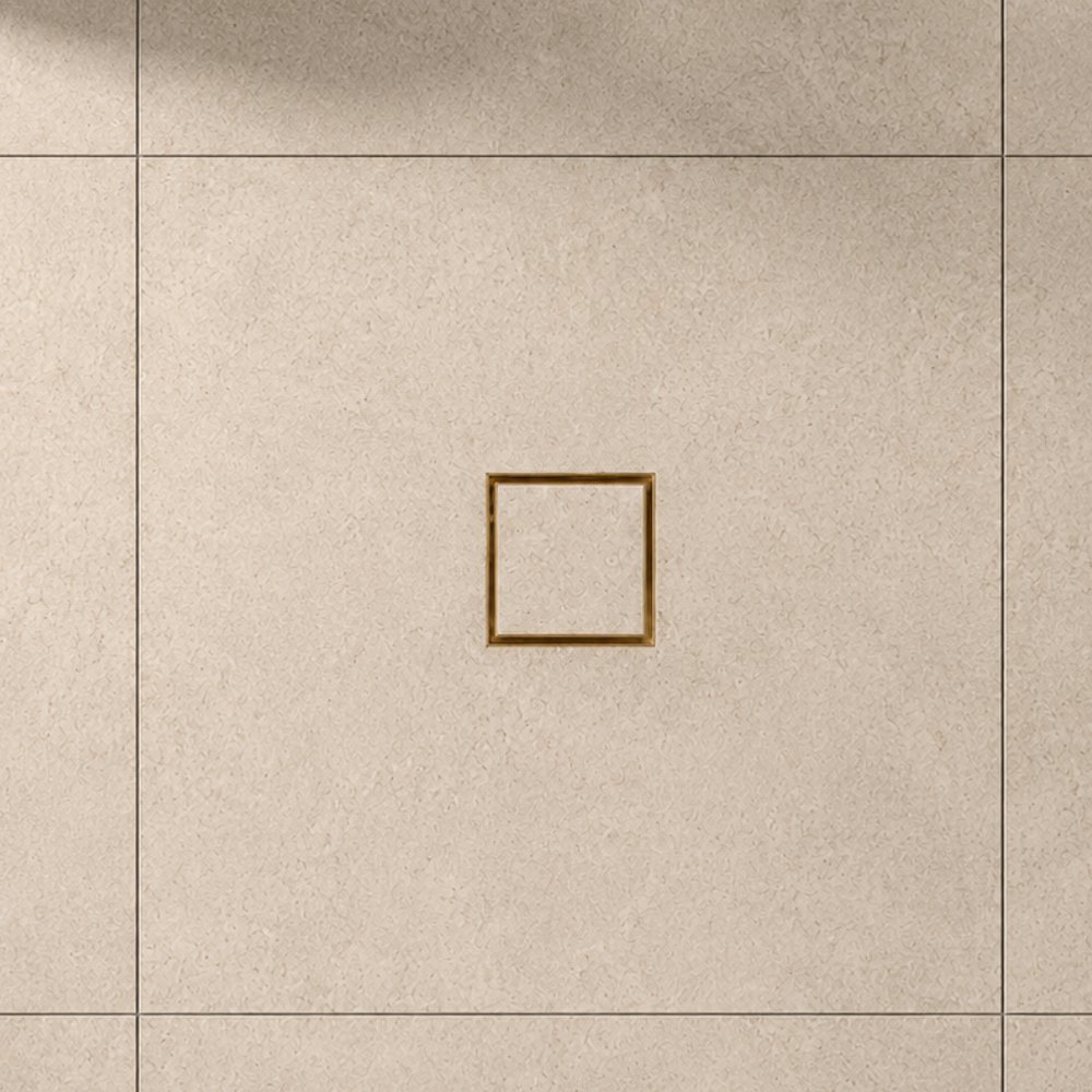 Brushed brass square tile insert grate set flush into a large-format tiled floor