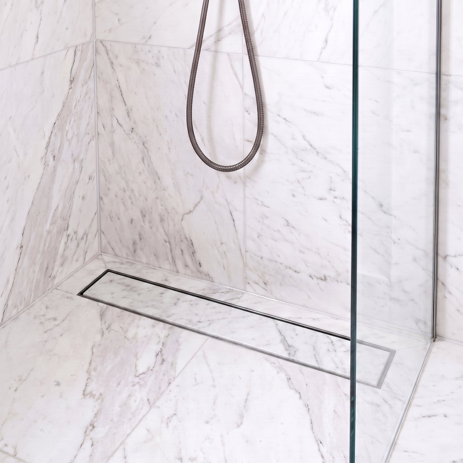 Gun metal linear tile insert drain installed in a white marble shower